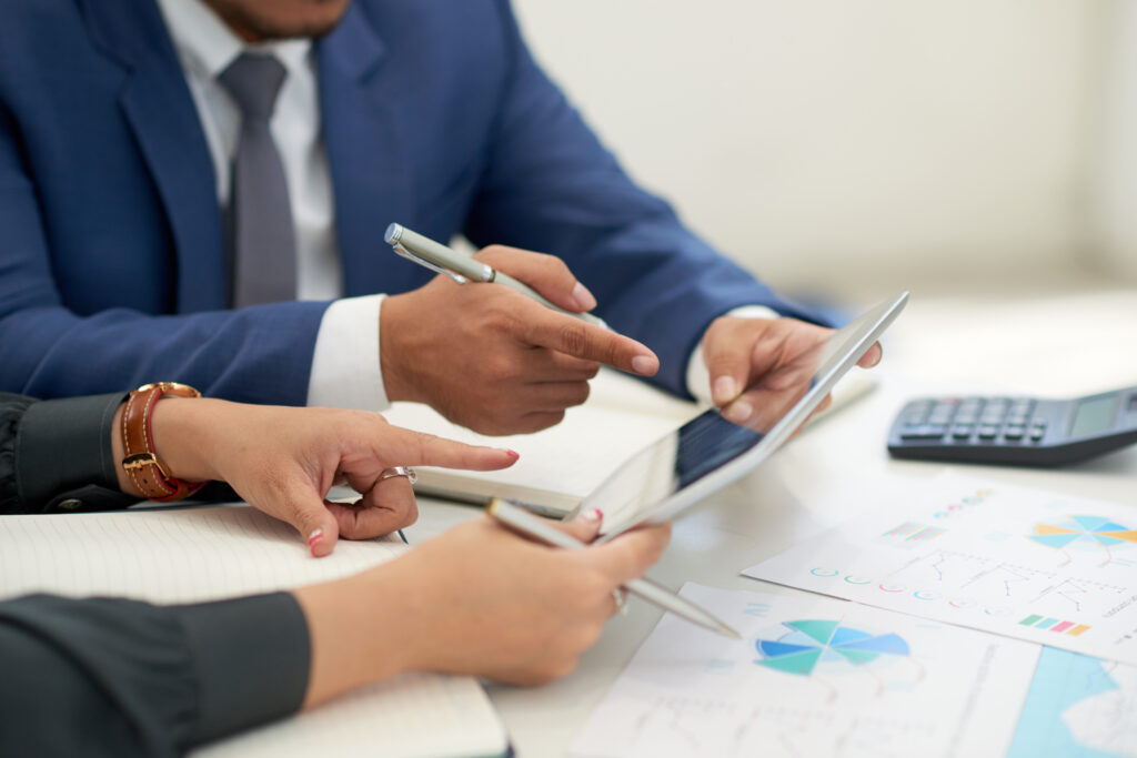 unrecognizable-business-people-sitting-meeting-with-charts-looking-pointing-tablet